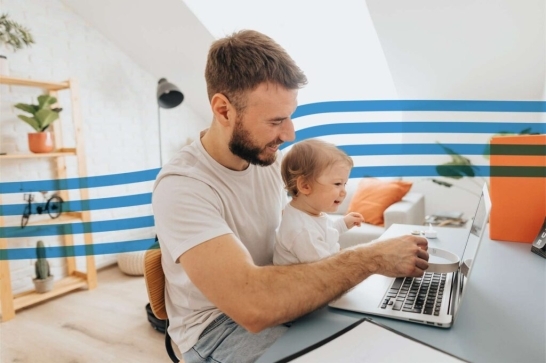 Father and toddler working together on a laptop at a bright home office with blue striped wall decor