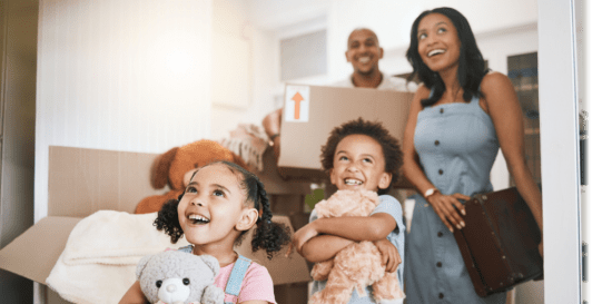 family smiling walking into new home with moving boxes.
