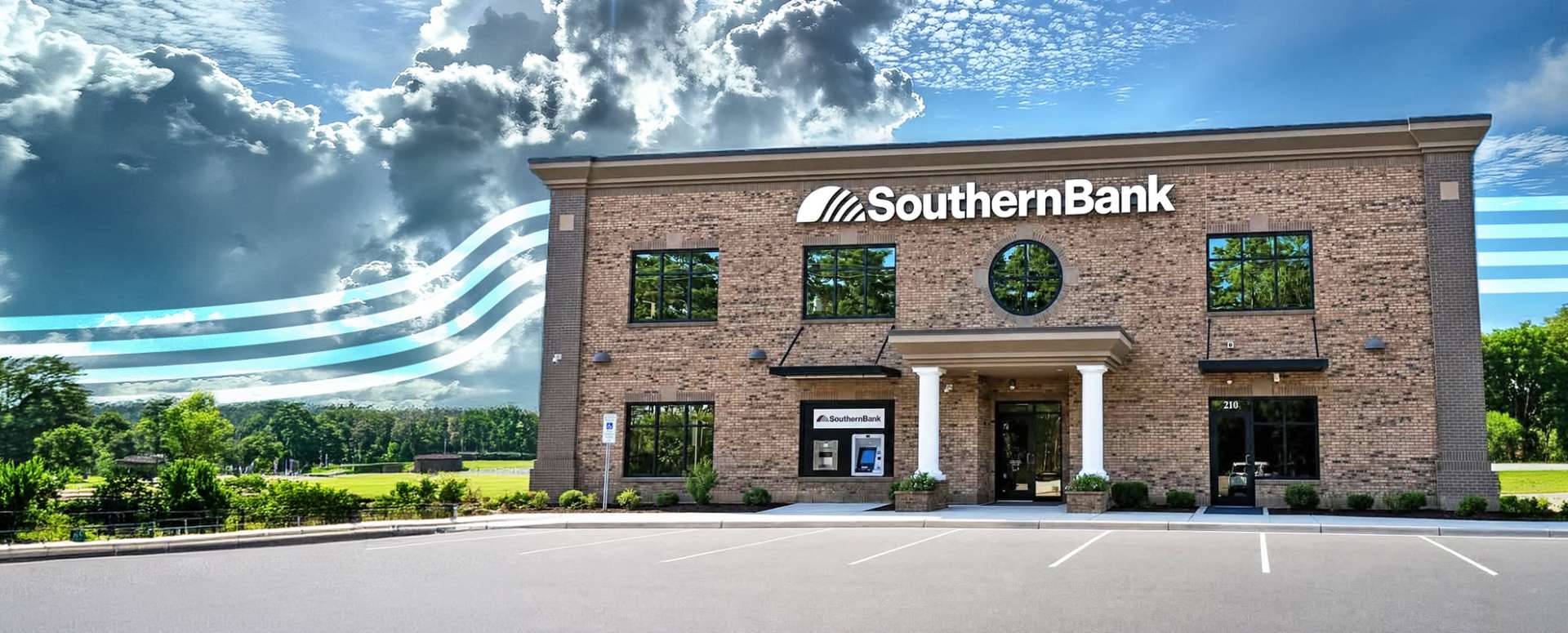 Southern Bank brick branch with large logo, front entry with columns, and a facing parking lot; sky features dramatic clouds and surreal blue waves on the left.