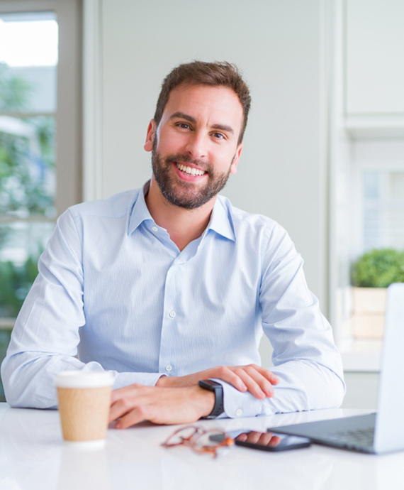 man with laptop smiling at camera