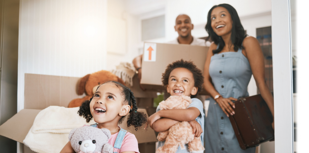 family smiling walking into new home with moving boxes.